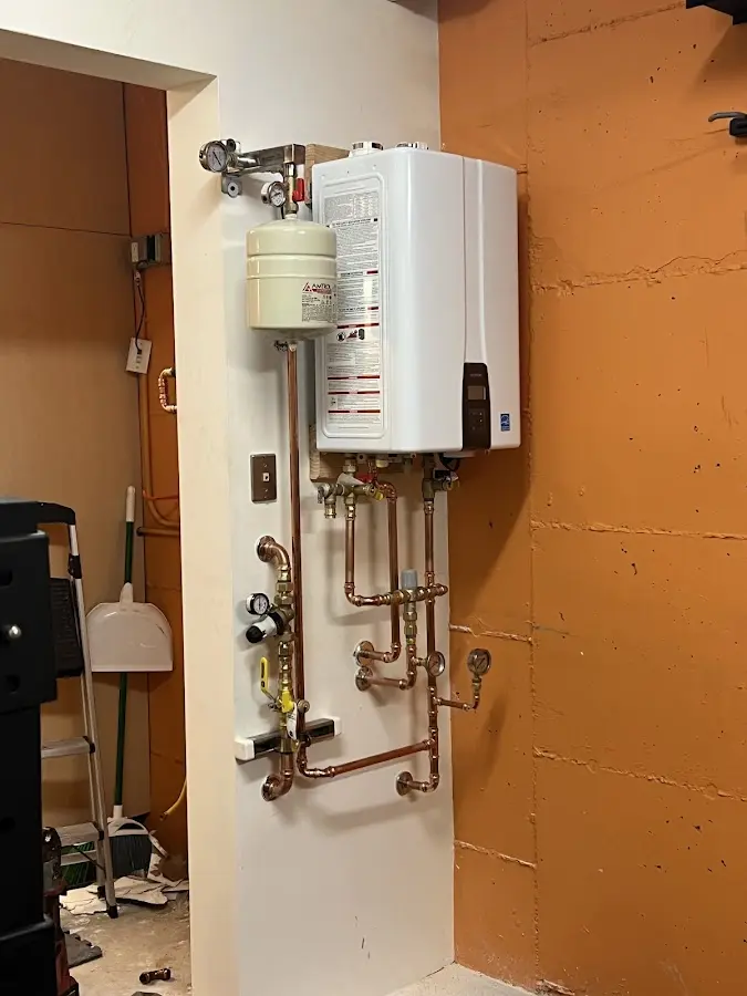 Plumbing technician inspecting water heater connections in Demarest